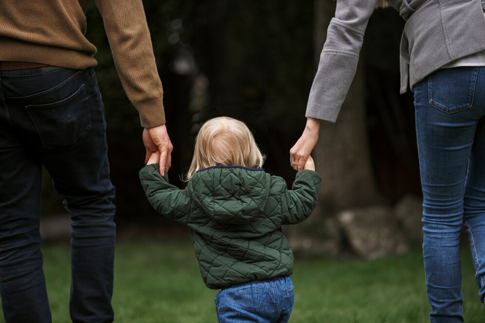 A man and a woman walking while holding their kid's hands